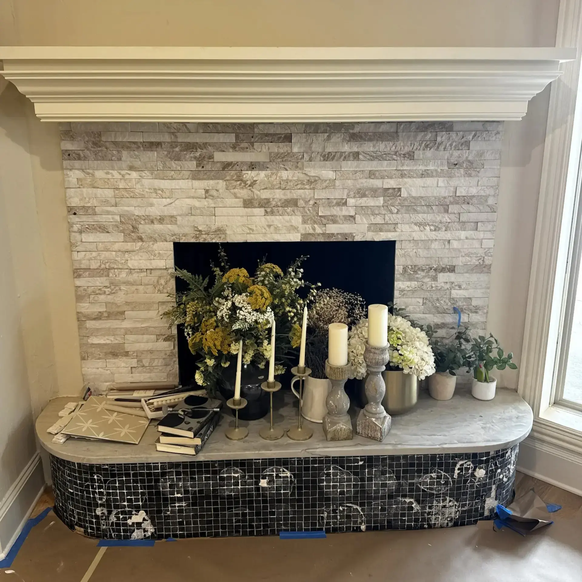 Beige painted corner wall with a stone fireplace, large and rounded tiled base, and large white accent piece on top